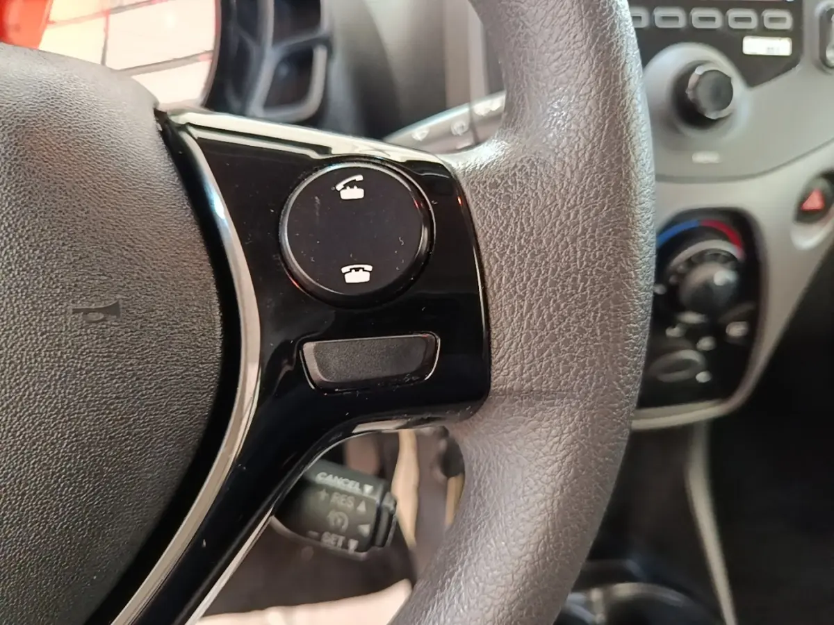Gros plan sur le volant multifonctions noir et gris de la Peugeot 108 VTI 72 S&S Active avec commandes d’appel intégrées.