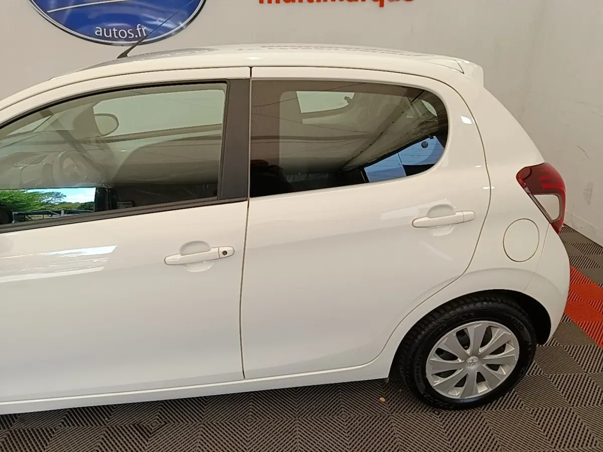 Profil droit d'une Peugeot 108 blanche de 2020, montrant les portières et la roue arrière sur sol intérieur.