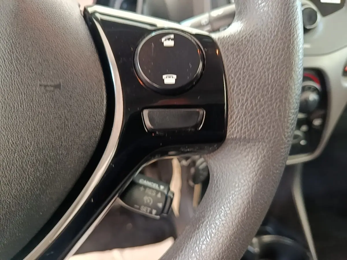 Gros plan sur le volant multifonctions gris de la Peugeot 108 blanc, avec commandes intégrées visibles.