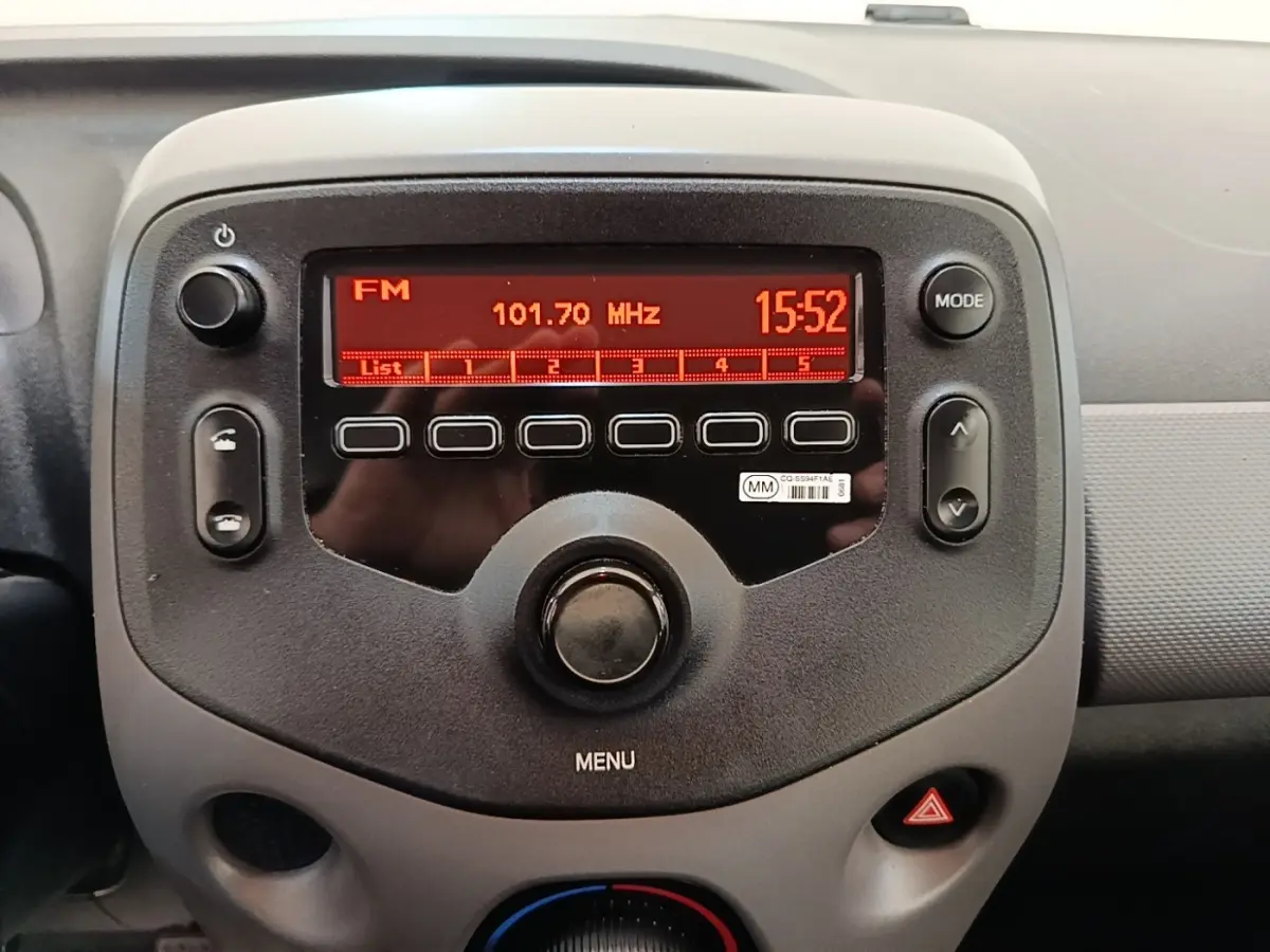 Vue rapprochée de la console centrale de la Peugeot 108 blanche, affichant la radio FM et les commandes multimédia.
