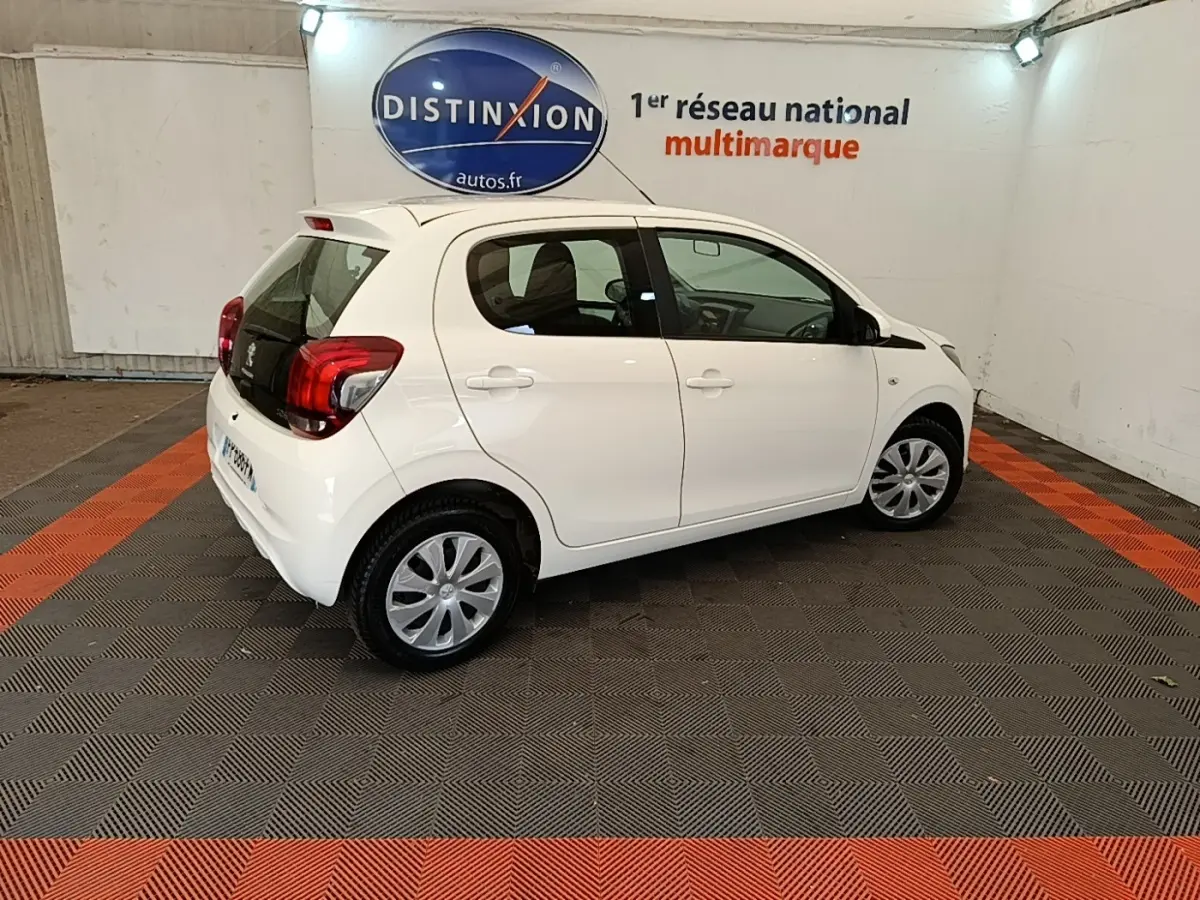 Peugeot 108 blanc vue de profil droit en intérieur, avec jantes acier et vitres teintées.