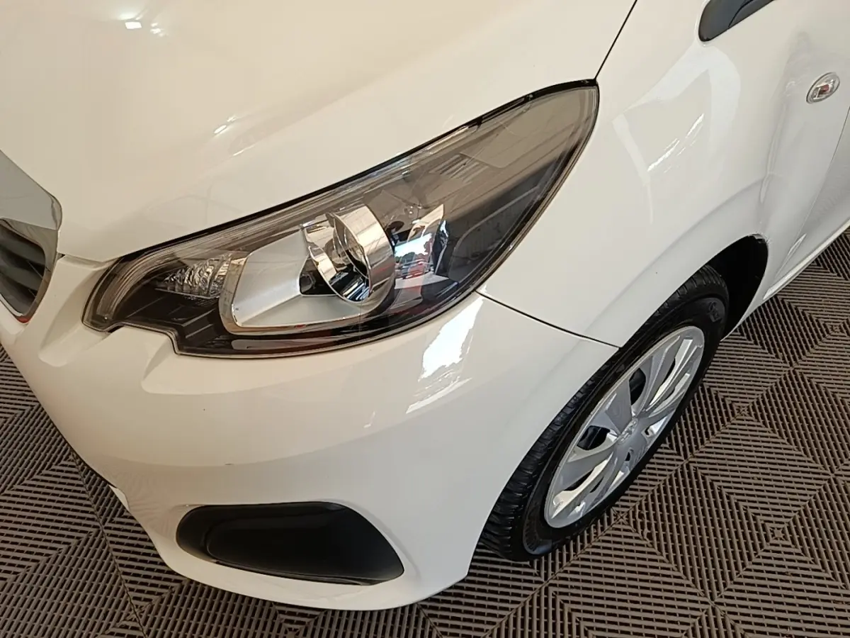 Gros plan sur l'avant droit blanc d'une Peugeot 108 VTI 72 S&S Active, mettant en valeur le phare et la roue.