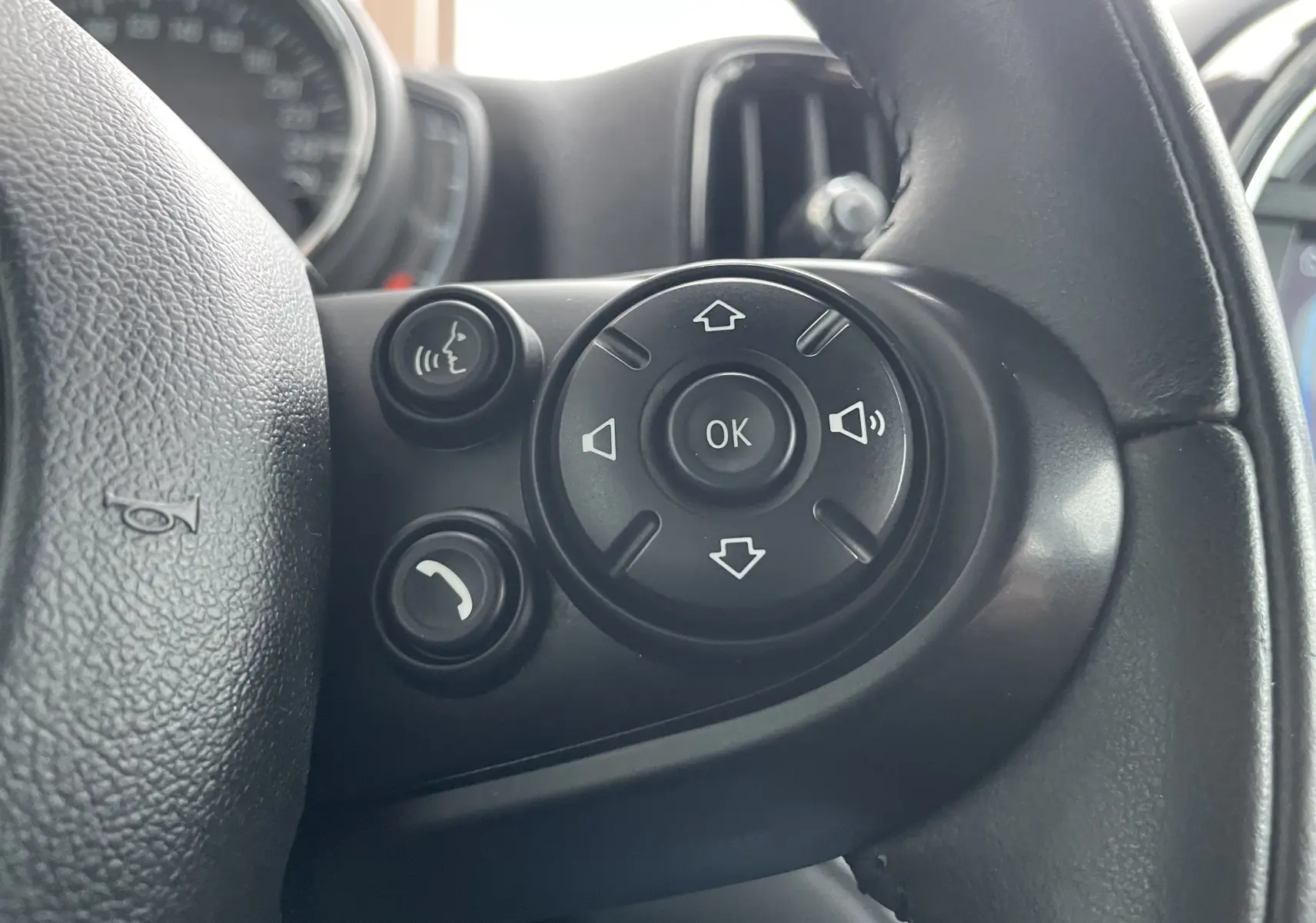 Gros plan sur les commandes vocales et de volume à droite du volant du MINI Countryman hybride bleu Island Metal de 2019.