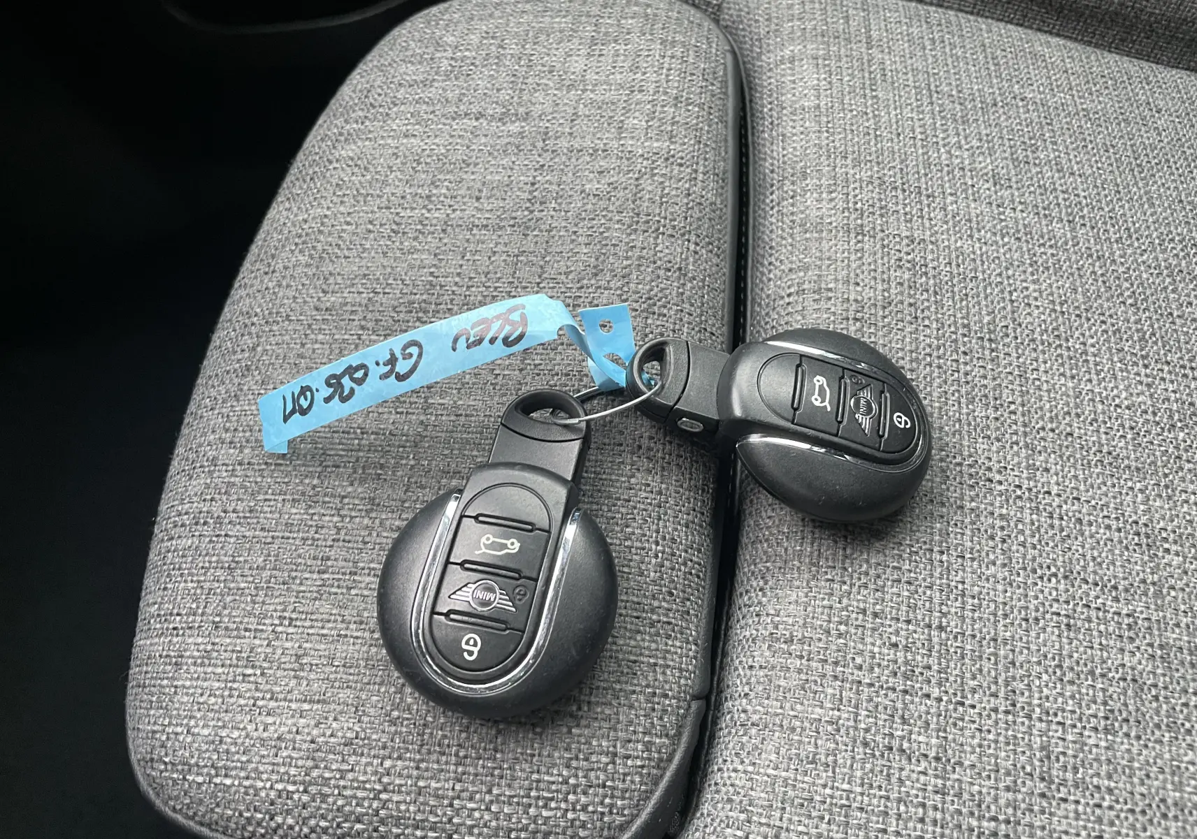 Gros plan sur deux clés MINI posées sur un accoudoir en tissu gris à l'intérieur du MINI Countryman hybride.