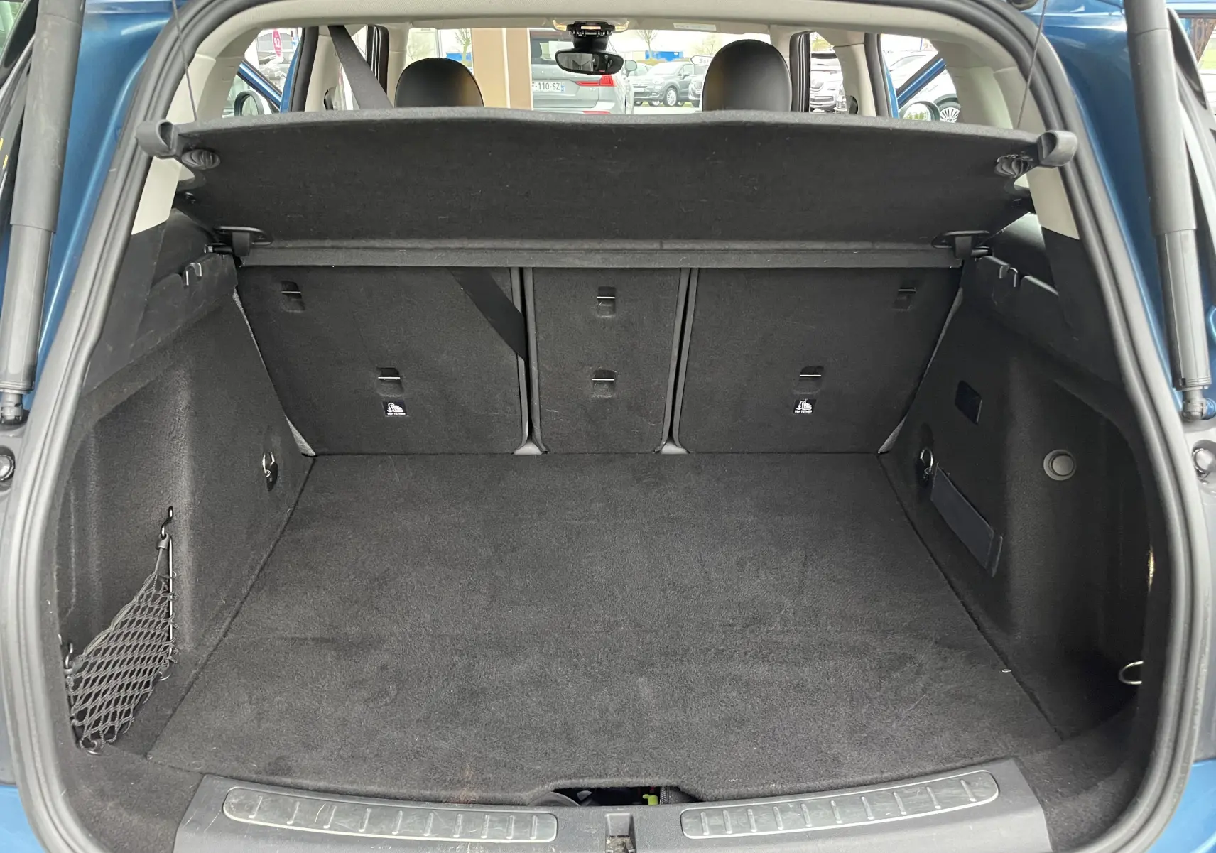 Coffre ouvert vu de l'arrière d'une MINI Countryman bleu Island Metal, montrant un espace de chargement propre et bien agencé.