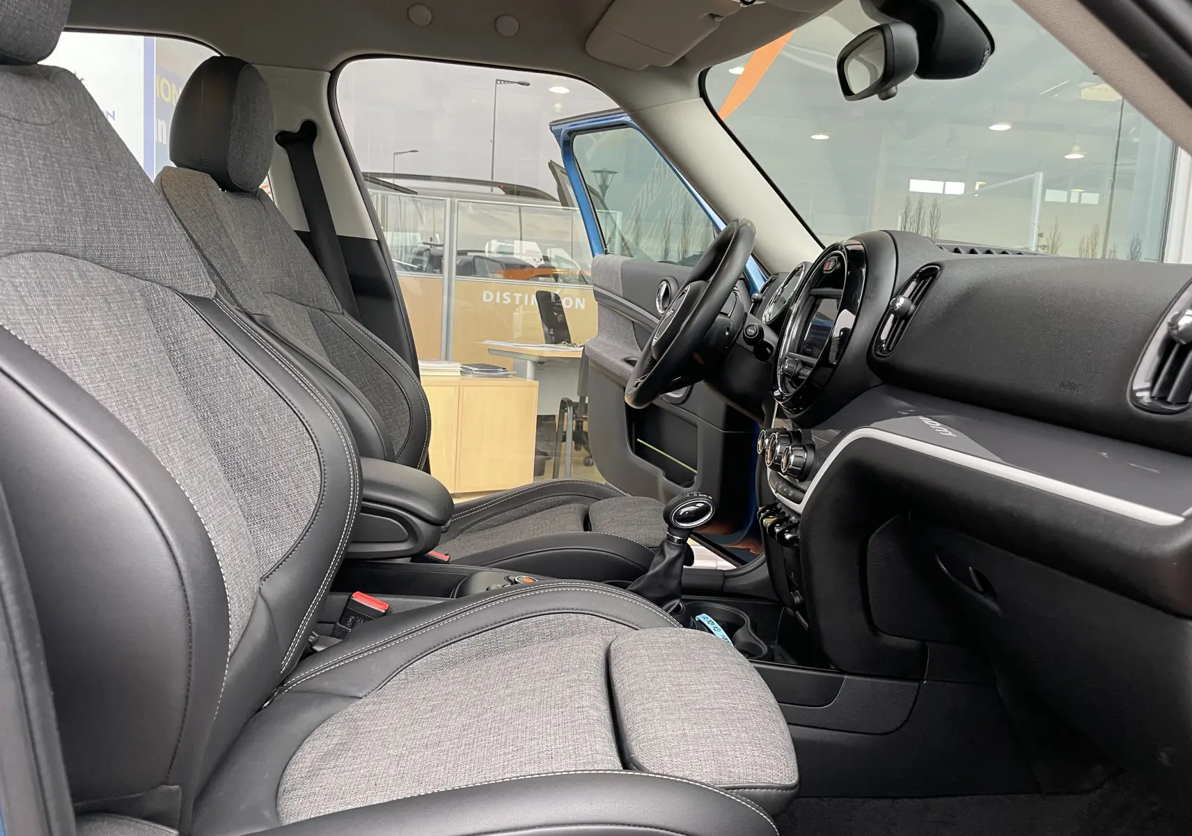 Intérieur avant du MINI Countryman hybride 2019 avec sièges tissu gris et cuir noir, volant et tableau de bord visibles.