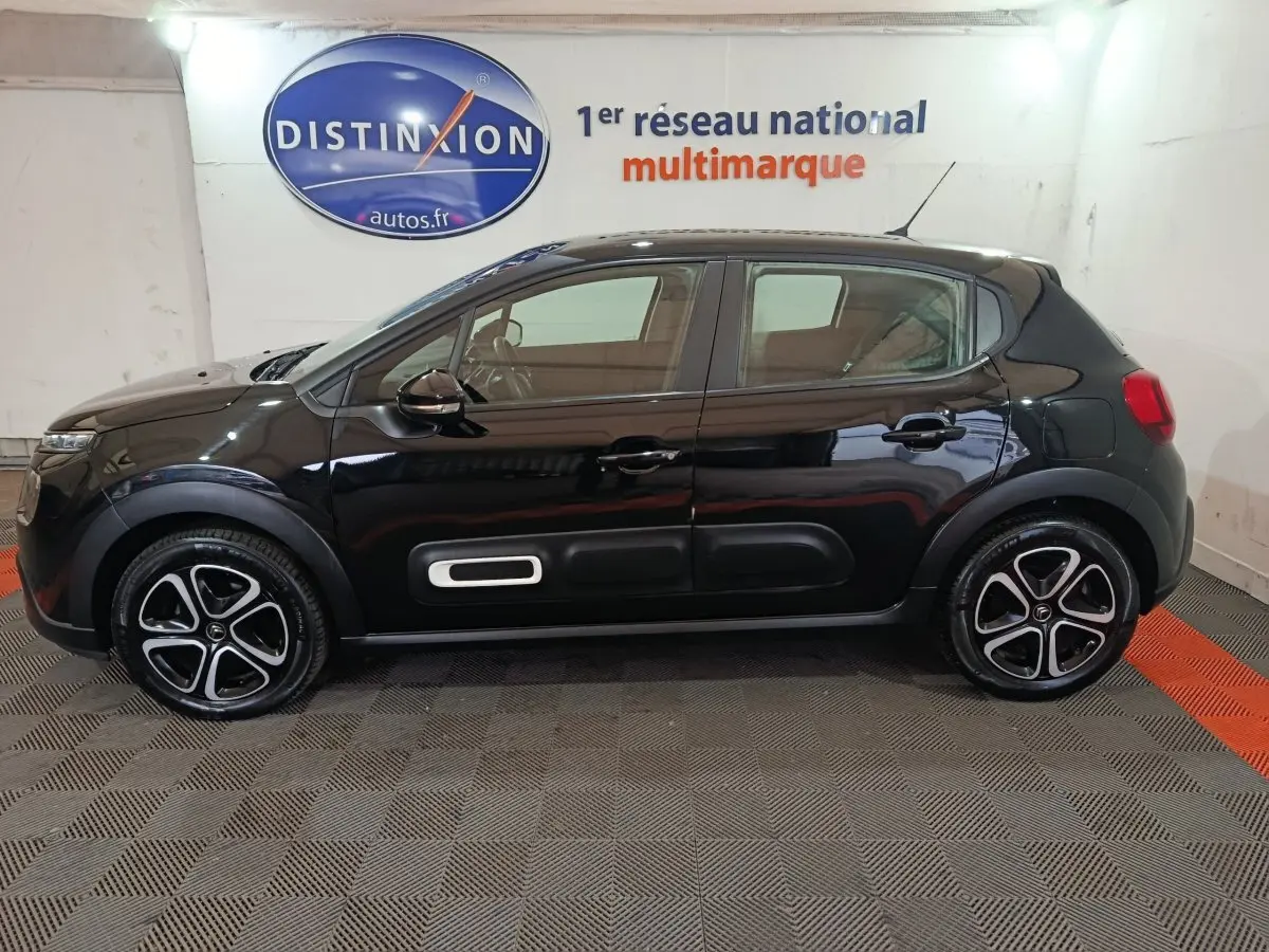 Profil latéral gauche d'une Citroën C3 noire 2024 avec protections latérales blanches et jantes stylisées.