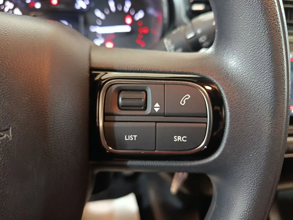 Gros plan sur les commandes gauche du volant noir multifonctions de la Citroën C3 2024 Diesel.