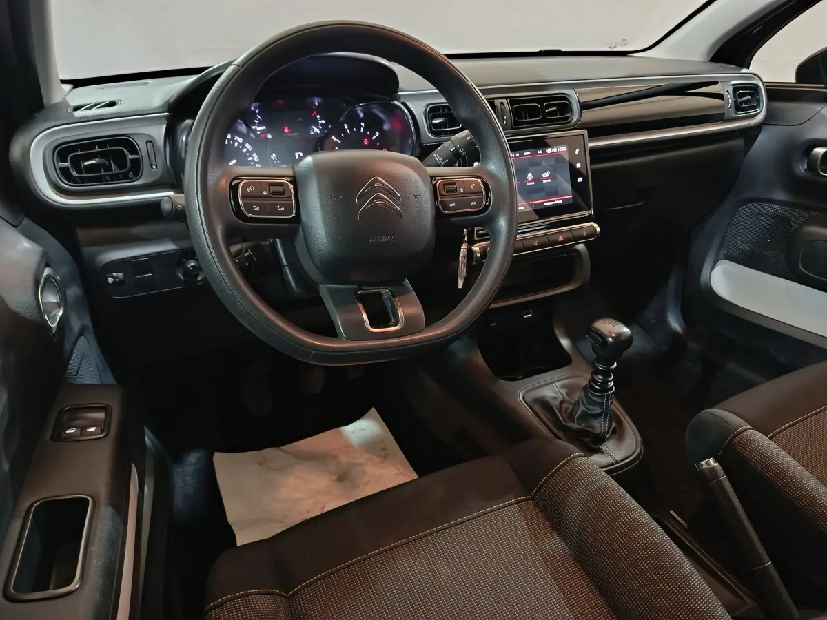 Vue intérieure côté conducteur de la Citroën C3 2024 noire, volant multifonctions et écran tactile central visible.