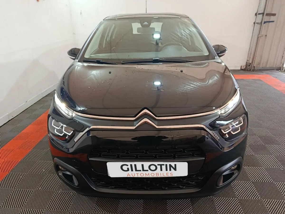 Vue avant d'une Citroën C3 noire 2024 avec phares LED et calandre chromée dans un garage.