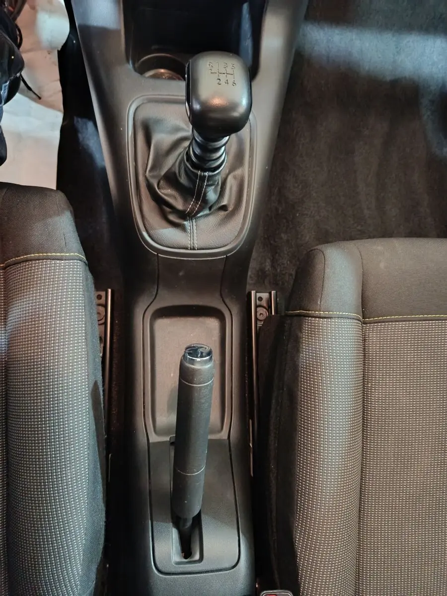 Vue plongeante sur la console centrale noire de la Citroën C3 2024, avec levier de vitesse manuel et frein à main.