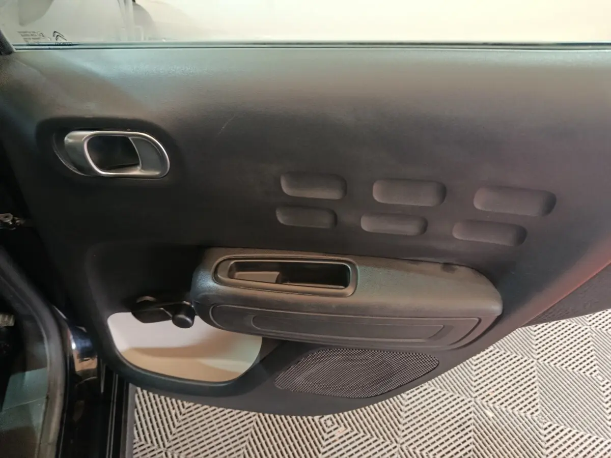 Vue rapprochée de la porte intérieure côté gauche noire de la Citroën C3 2024 avec poignée et haut-parleur intégrés.