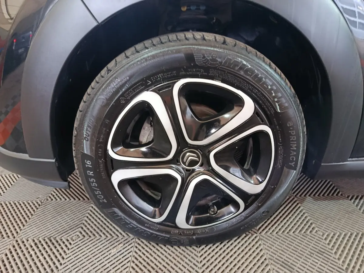 Gros plan sur la roue avant gauche noire d'une Citroën C3 2024 avec jante alliage bicolore et pneu Michelin.