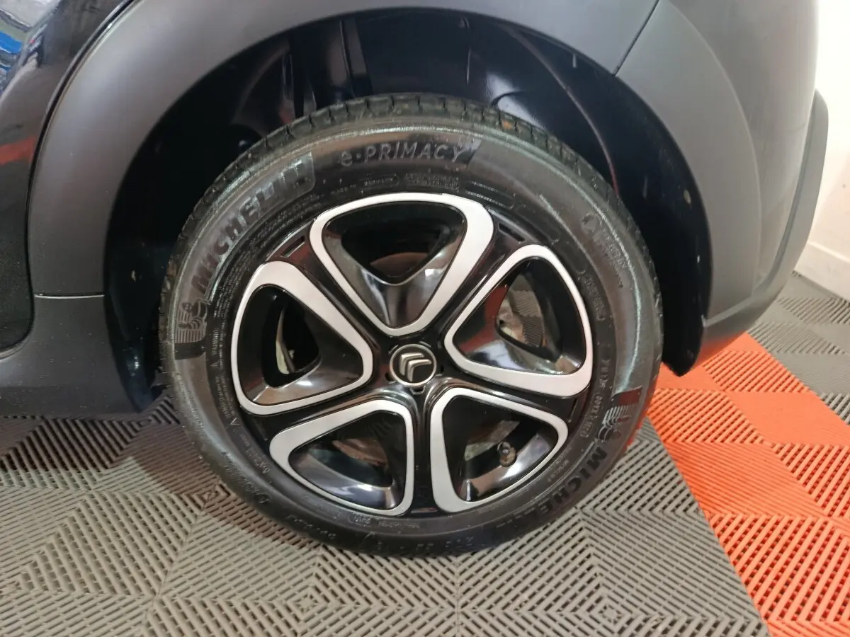 Gros plan sur la roue avant droite noire d'une Citroën C3 2024 avec jante alliage au design moderne.