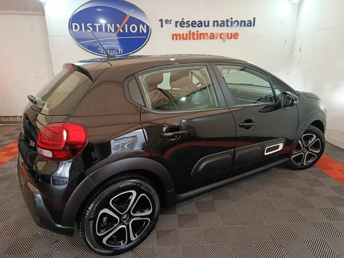 Citroën C3 noire vue 3/4 arrière droit, avec jantes alliage distinctives et protections latérales blanches.