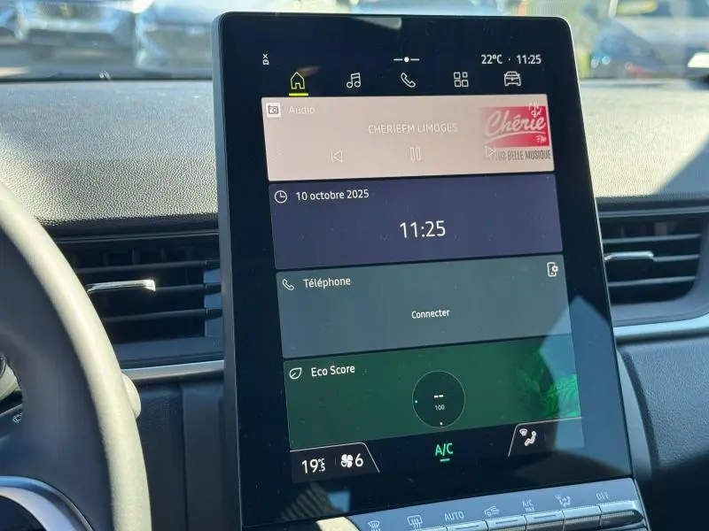 Intérieur de Renault Captur 2025, écran tactile central affichant radio, téléphone et score éco, vue de face.
