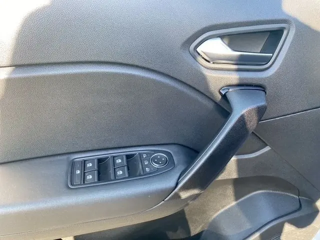 Détail de la porte côté conducteur du Renault Captur gris clair 2023, avec commandes électriques des vitres et poignée noire.