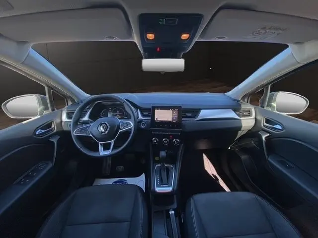 Vue intérieure avant du Renault Captur gris clair 2023, volant multifonctions cuir synthétique et écran tactile central.