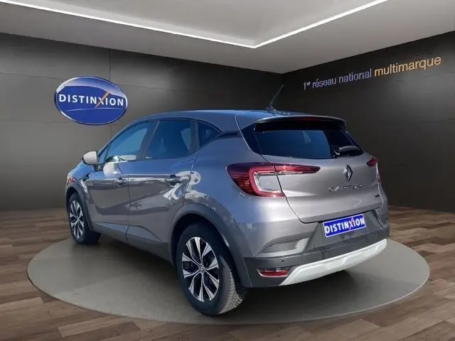 Vue 3/4 arrière droite du Renault Captur gris clair 2023 en hybride, avec jantes alliage et feux LED distinctifs.
