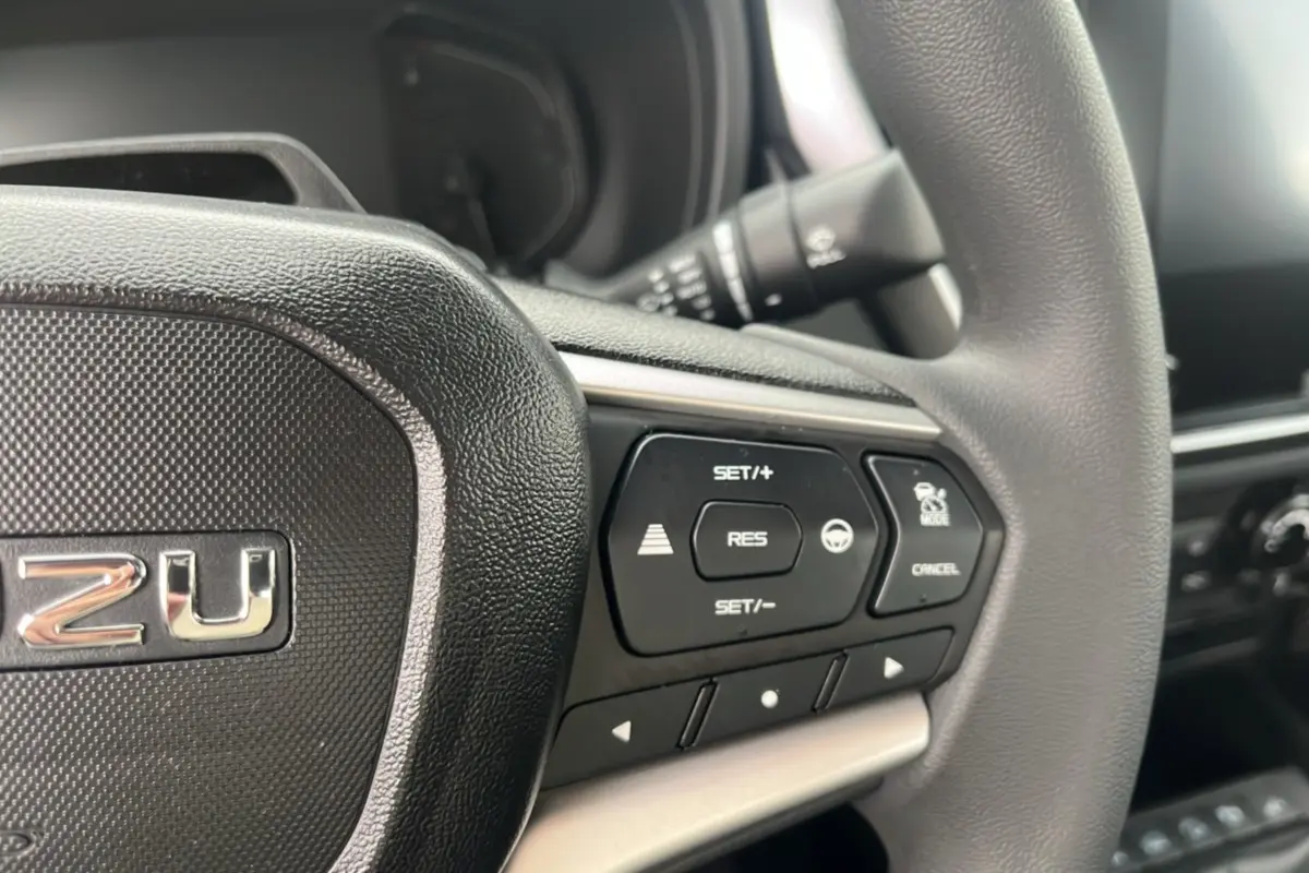 Gros plan sur le volant multifonctions noir de l'Isuzu D-MAX 2.2 TD 164 Space Evolution avec commandes de régulateur.