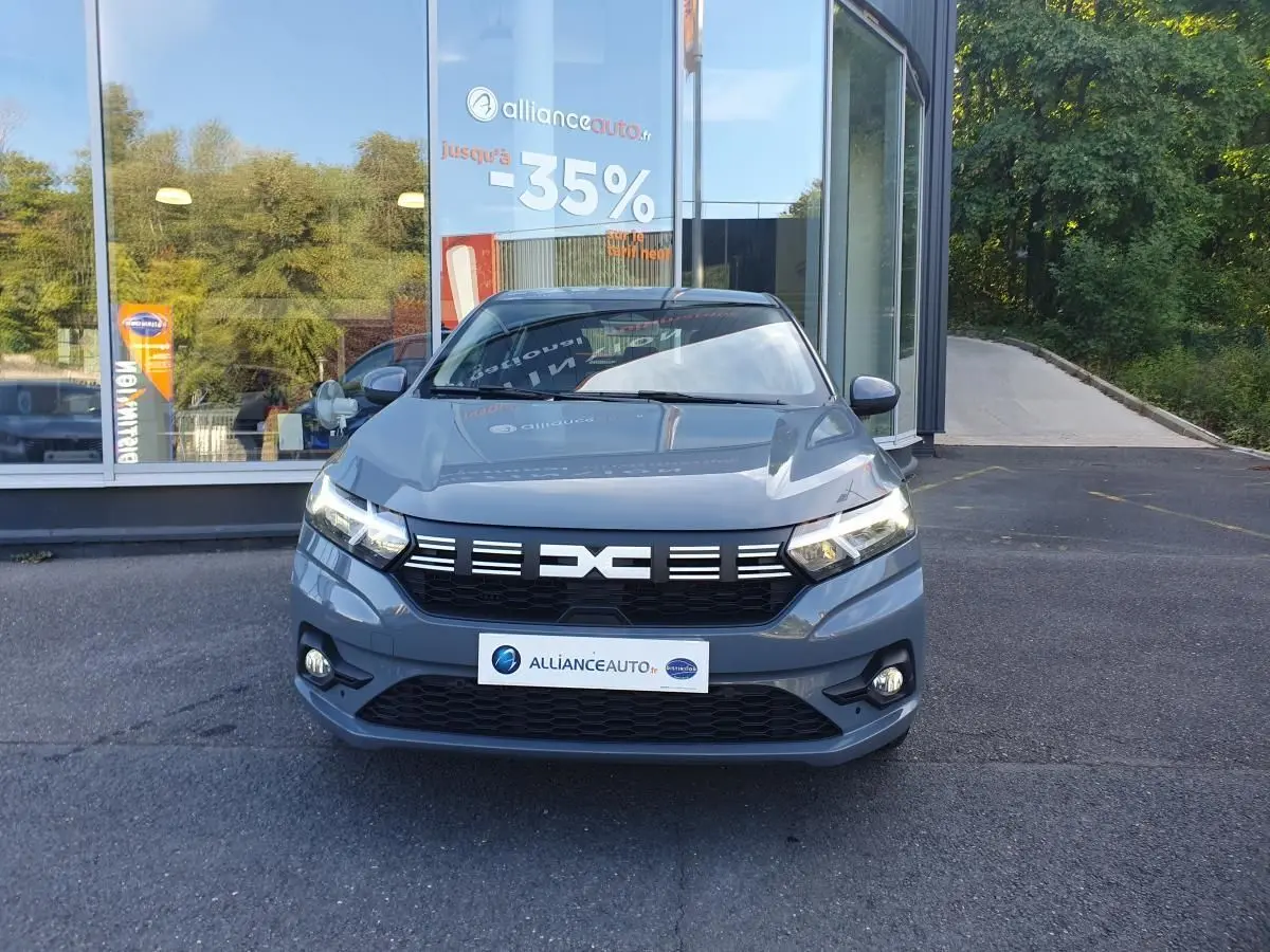 Vue avant d'une Dacia Sandero gris urbain 2024 avec signature lumineuse LED et calandre noire distinctive.