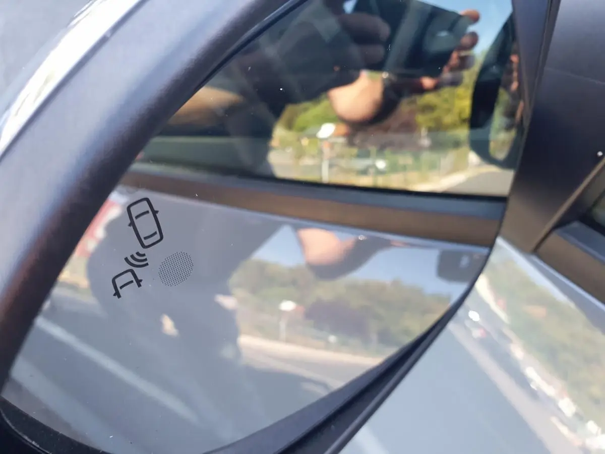 Rétroviseur droit de la Dacia Sandero gris urbain 2024 avec alerte d'angle mort visible sur le miroir.
