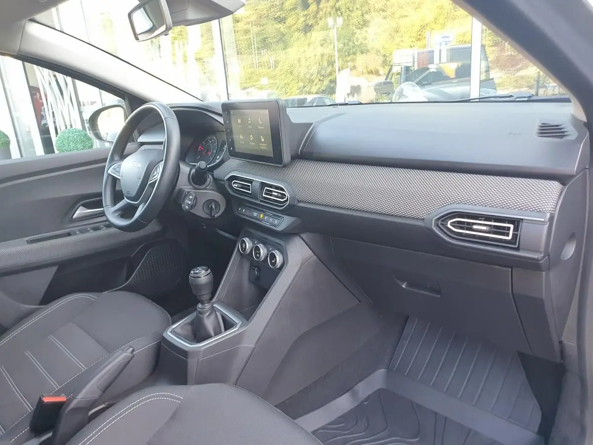 Intérieur de la Dacia Sandero 2024 vu côté conducteur, tableau de bord moderne avec écran tactile et finition grise.