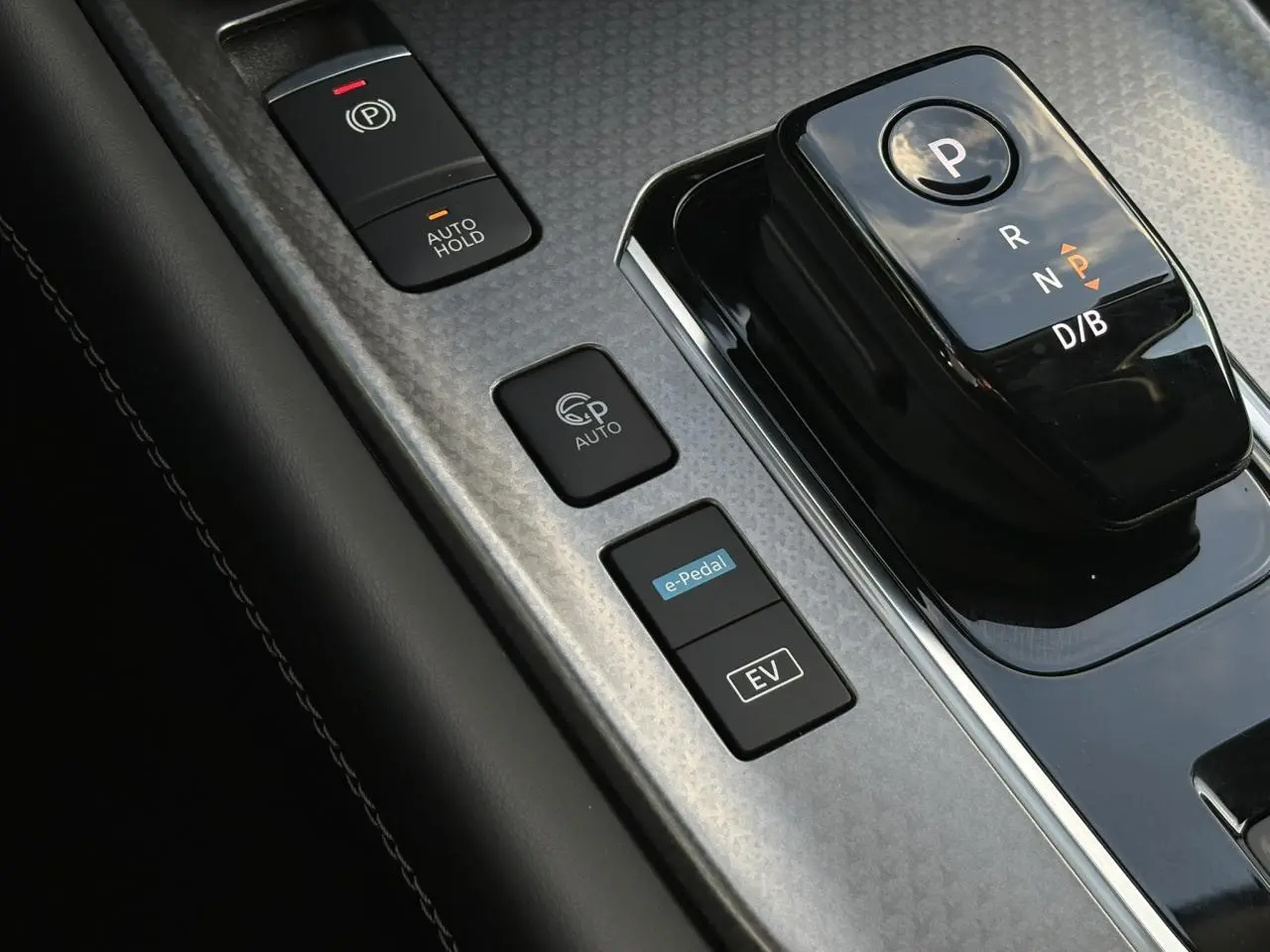 Gros plan sur la console centrale noire et grise du Nissan Qashqai III avec sélecteur de boîte auto et boutons e-Pedal et EV.