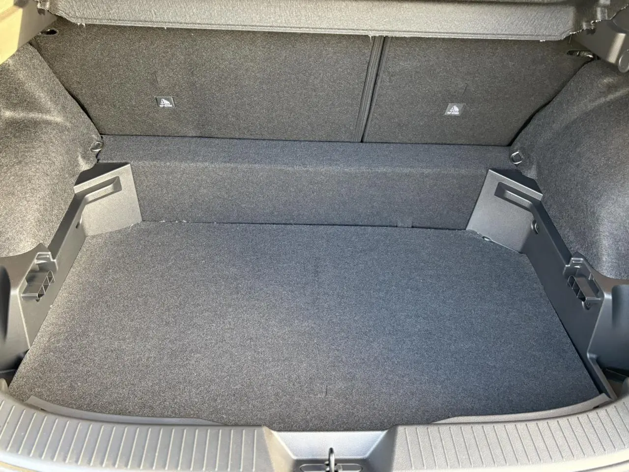 Coffre ouvert du Nissan Qashqai III noir Kuro, vue intérieure montrant le tapis et les parois en tissu gris.