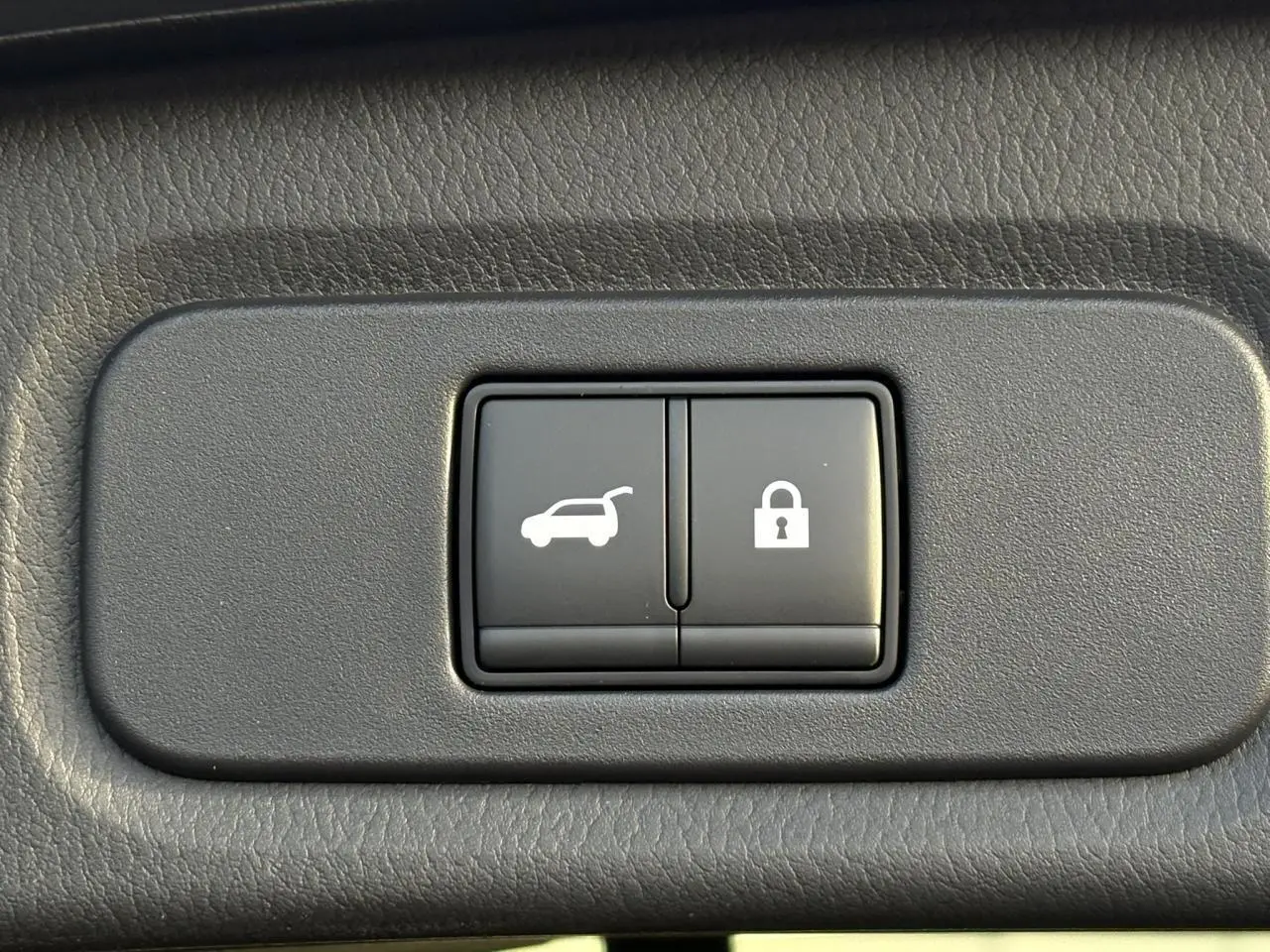 Boutons noirs pour hayon électrique et verrouillage, intégrés dans le panneau intérieur du Nissan Qashqai noir.