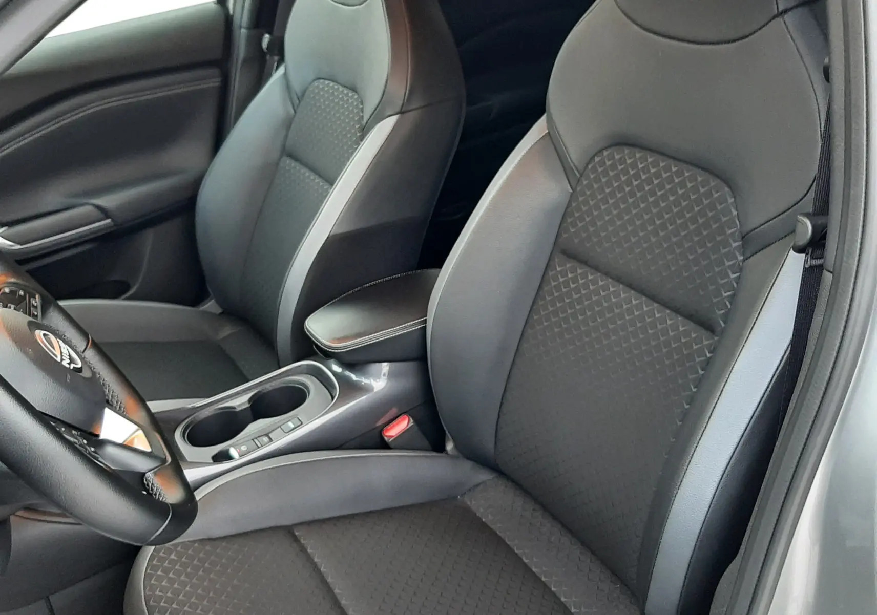 Intérieur du Nissan Juke 2024 gris perle métal, vue côté conducteur sur les sièges en cuir gris et console centrale.