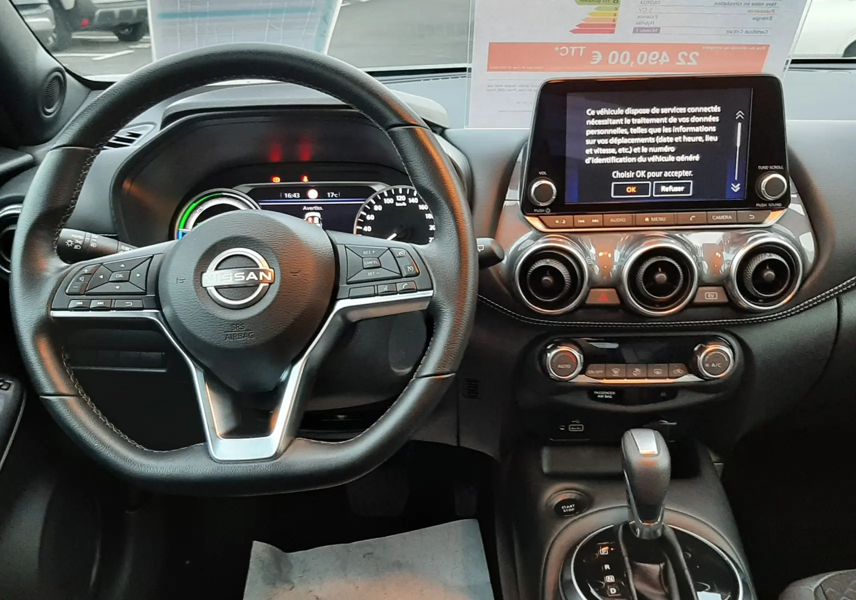 Intérieur du Nissan Juke 2024 1.6 HEV N-Connecta, vue du poste de conduite avec volant multifonction et écran tactile central.