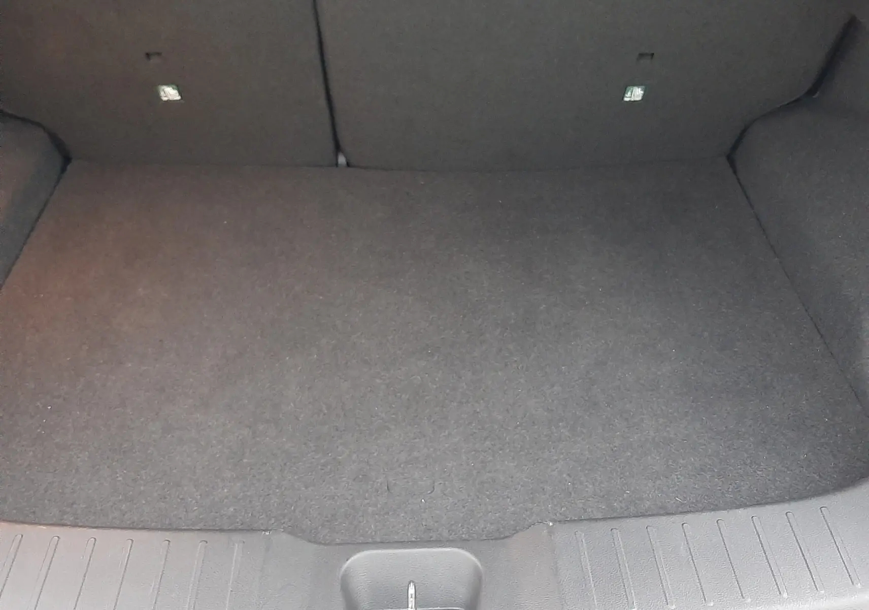 Coffre spacieux et vide du Nissan Juke 2024 gris perle métal, vue intérieure depuis l'arrière du véhicule.