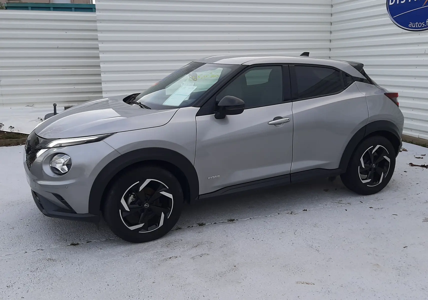 Nissan Juke 2024 gris perle métal vu de profil côté gauche, avec jantes noires et toit noir contrasté.