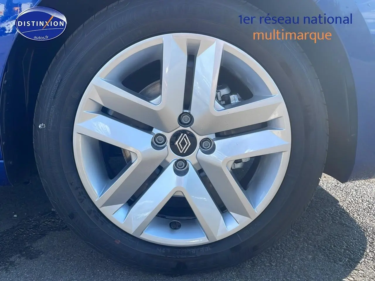 Gros plan sur la jante alliage argentée de la Renault Clio V bleu iron, mettant en valeur le logo central Renault.