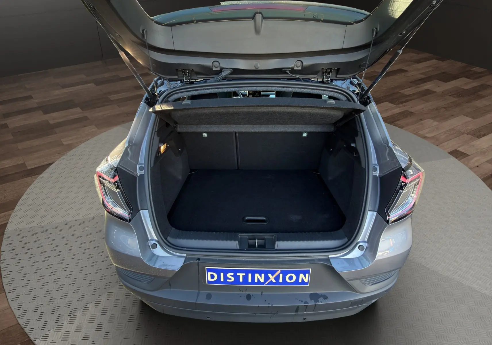 Vue arrière du Renault Captur 2024 gris Cassiopée avec coffre ouvert et toit noir, montrant l'espace de chargement vide.