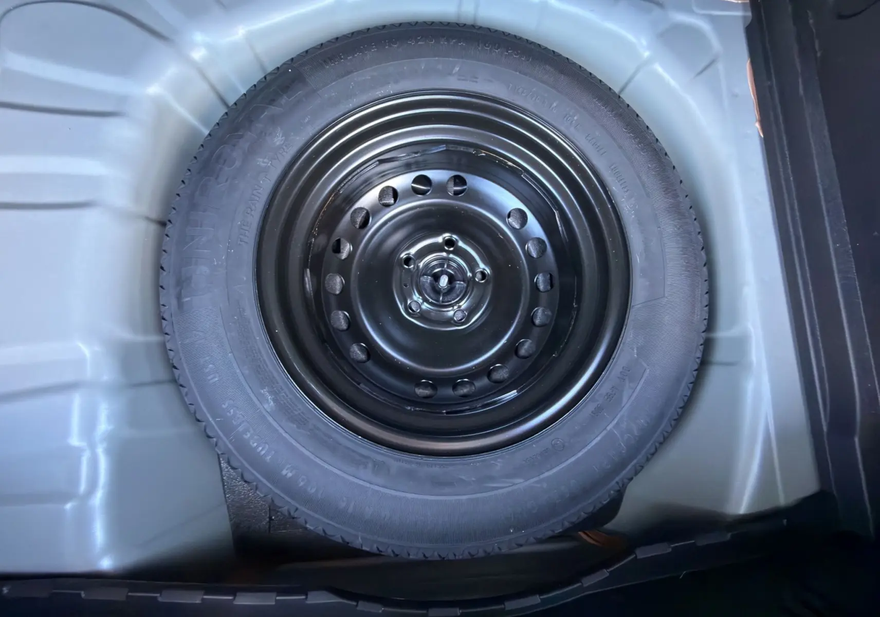 Gros plan sur la roue de secours noire dans le coffre du Renault Captur 2024 gris Cassiopée toit noir.