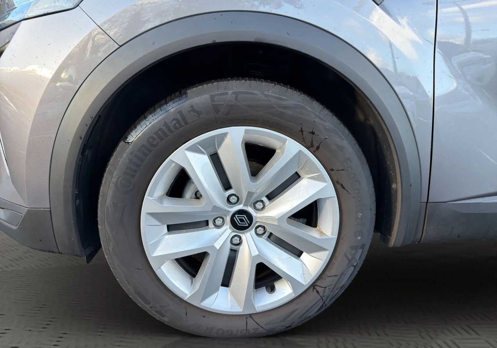 Gros plan sur la roue avant gauche du Renault Captur gris Cassiopée avec jante alliage et logo Renault central.