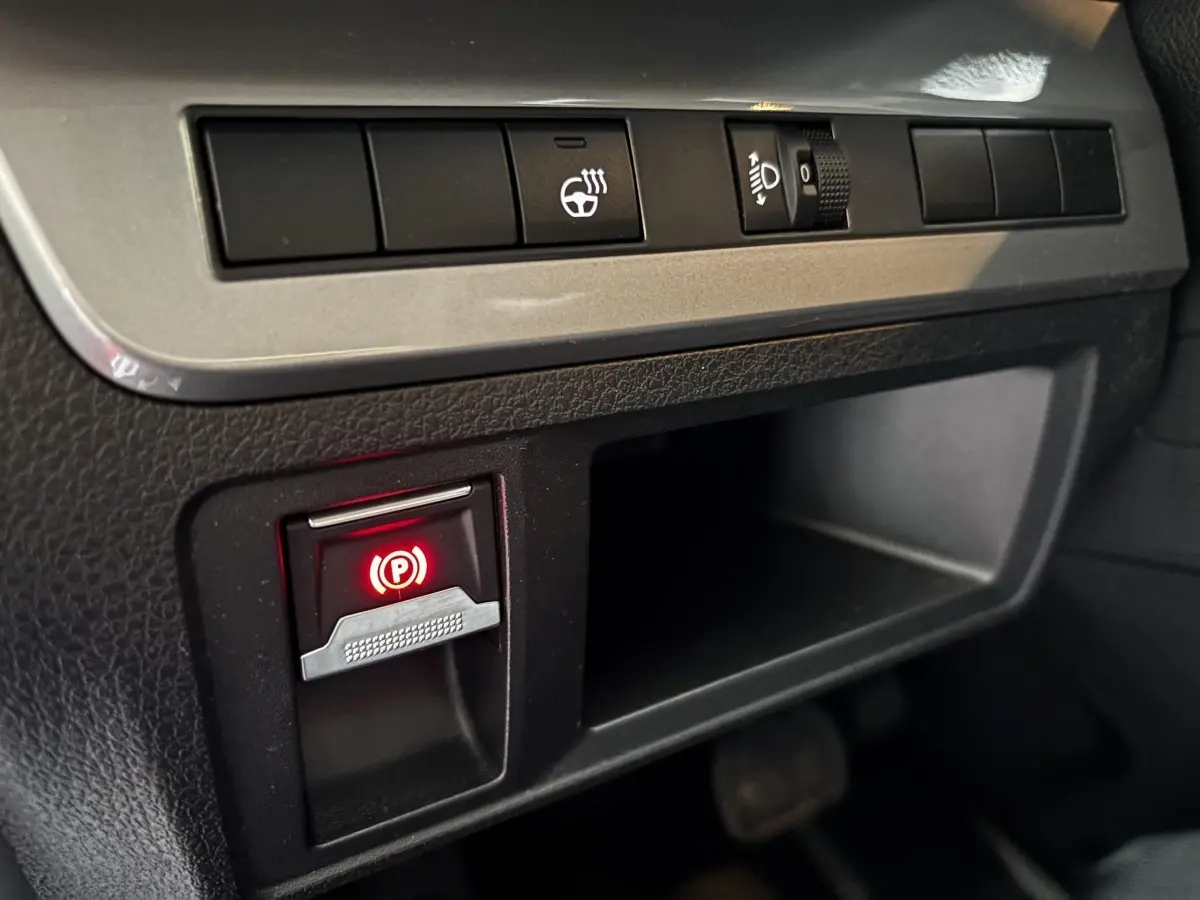 Gros plan sur les commandes du frein à main électrique et réglage des phares dans l'habitacle du FIAT Scudo Fourgon noir 2025.