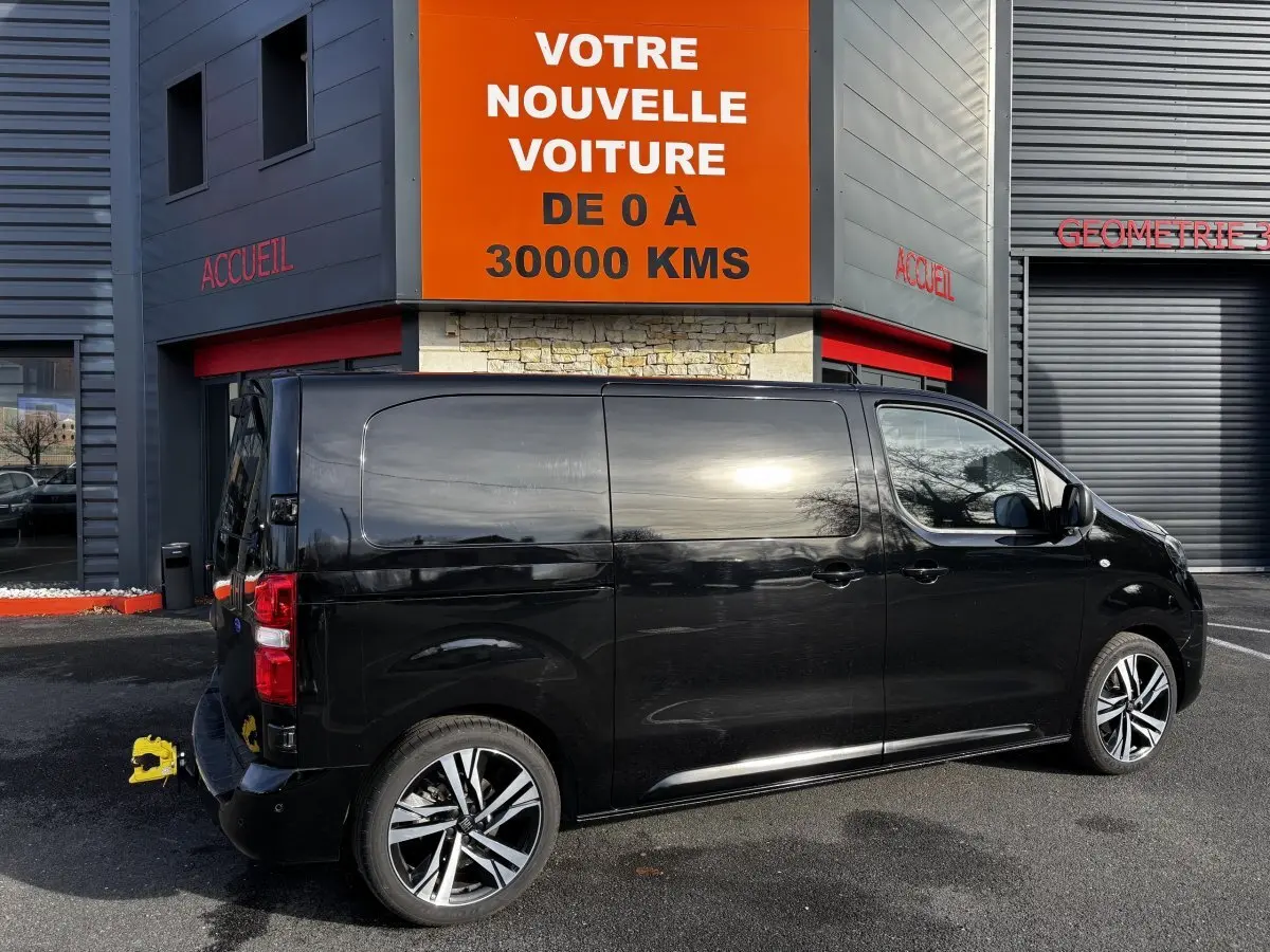 FIAT Scudo Fourgon noir vu de profil côté droit, stationné devant un bâtiment avec enseigne orange.