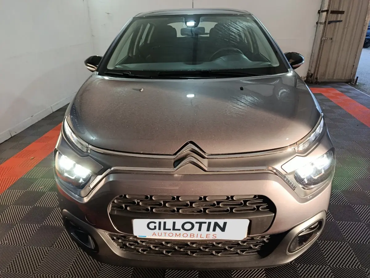 Vue avant d'une Citroën C3 2024 gris foncé avec phares LED allumés dans un garage.