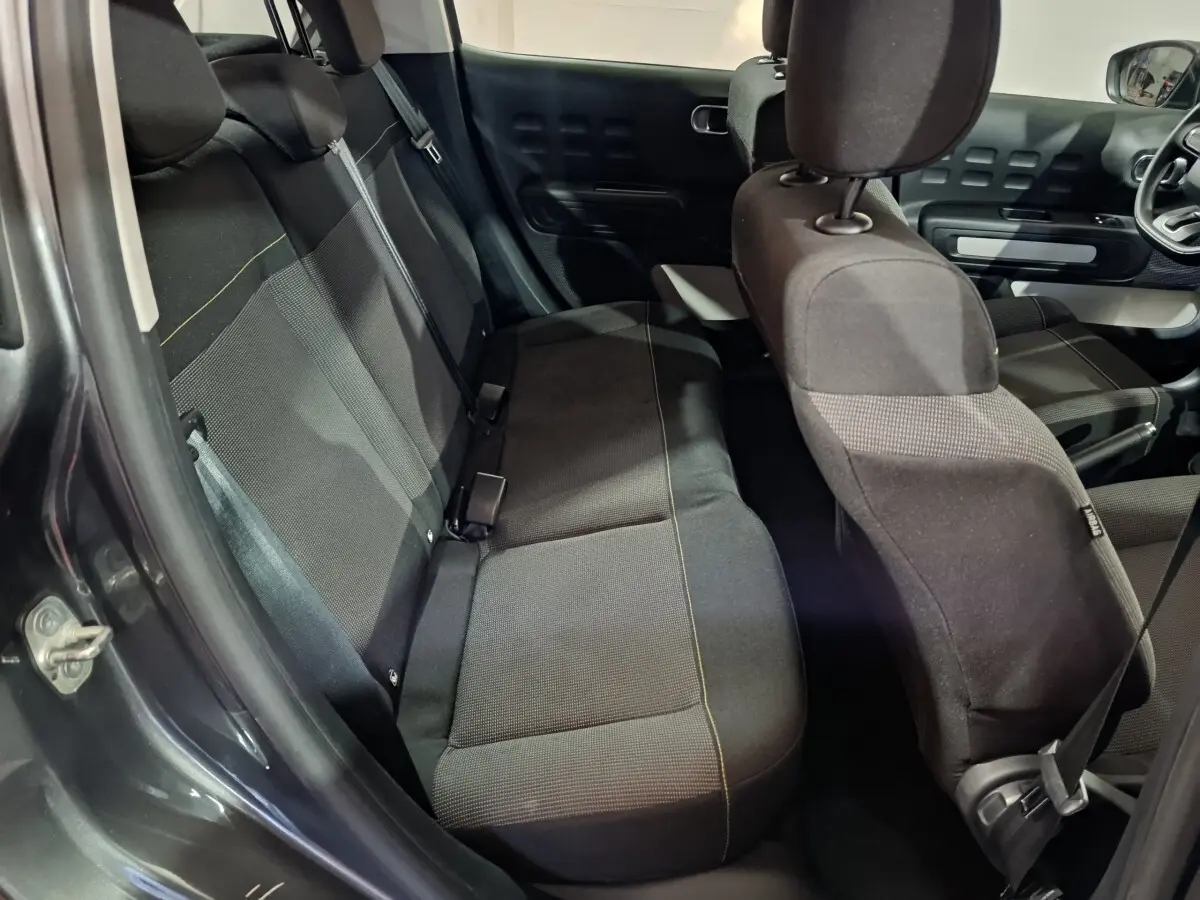 Vue intérieure côté gauche montrant la banquette arrière et les sièges avant noirs de la Citroën C3 gris foncé 2024.