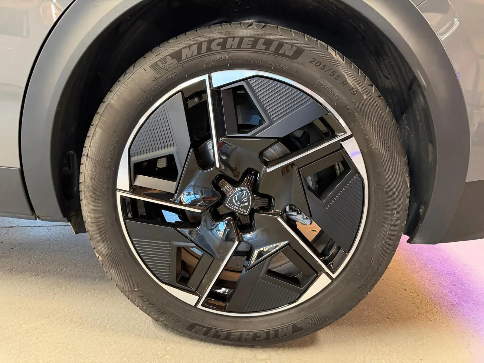 Gros plan sur la jante alliage 19'' diamantée graphite du Peugeot 408 gris, avec logo Peugeot central visible.