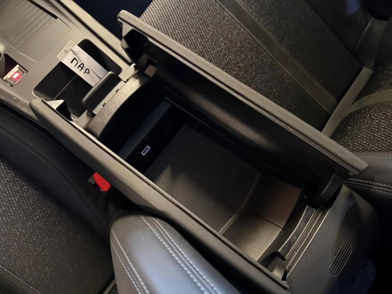 Vue rapprochée de la console centrale ouverte avec rangement intérieur et surpiqûres Vert Adamite dans une Peugeot 408 gris Selenium.