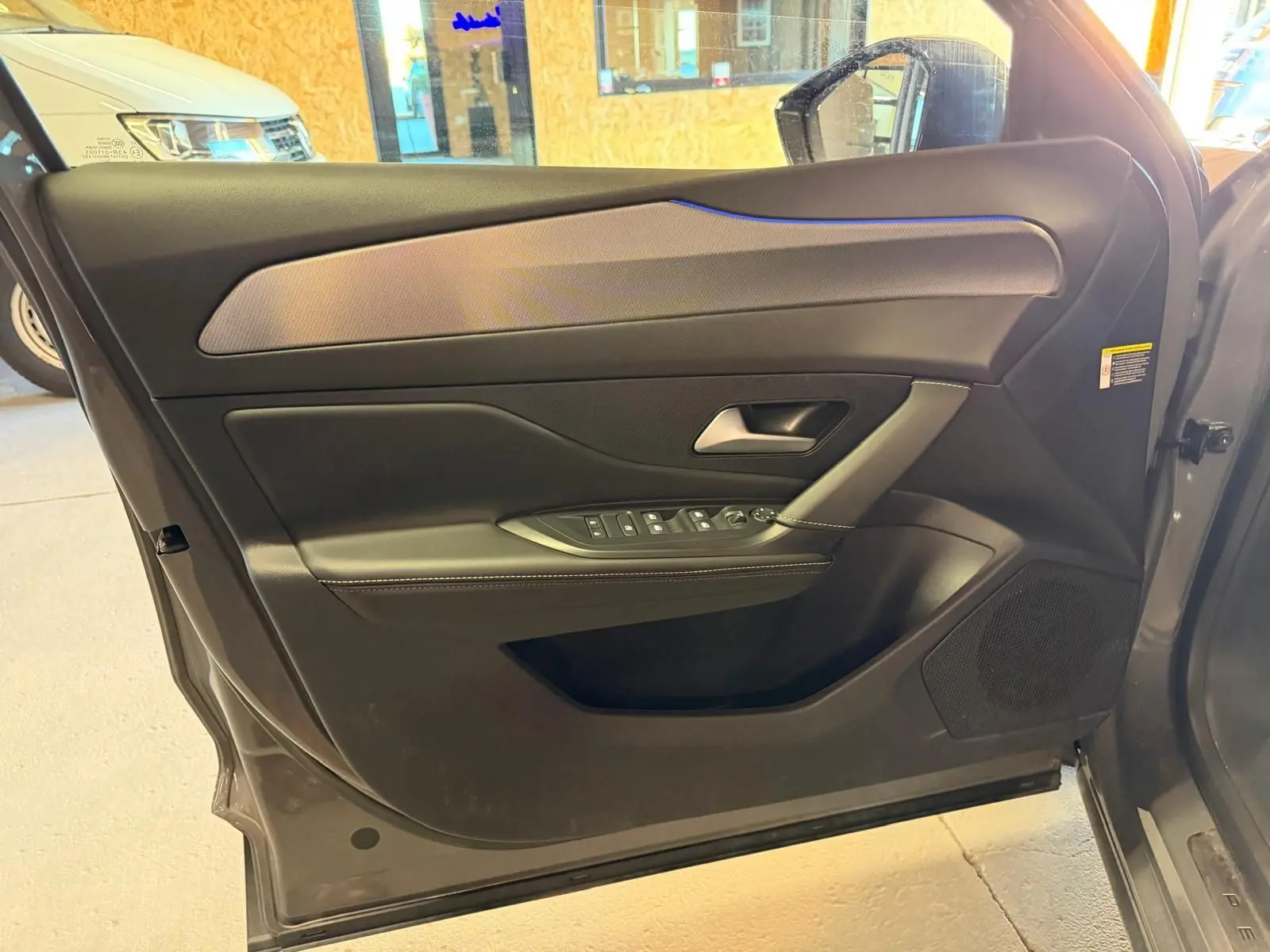 Vue intérieure de la porte avant gauche grise du Peugeot 408 2025 avec garniture noire et surpiqûres claires.