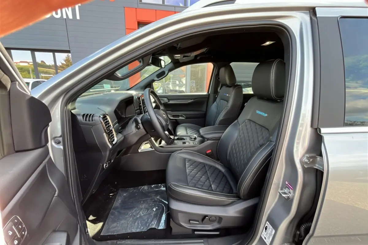 Vue intérieure côté conducteur du Ford Ranger gris iconic 2026, sièges cuir noirs avec surpiqûres et logo Platinum Rideau.