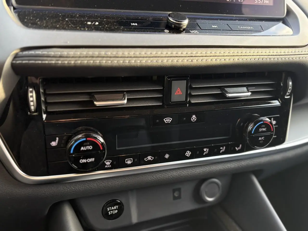 Vue rapprochée de la console centrale du Nissan Qashqai noir, montrant les commandes de climatisation automatique bi-zone et le bouton Start/Stop.