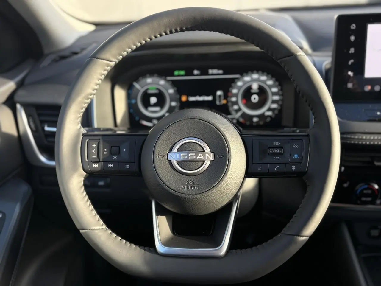Vue rapprochée du volant noir du Nissan Qashqai 2026 avec commandes intégrées et tableau de bord numérique en arrière-plan.