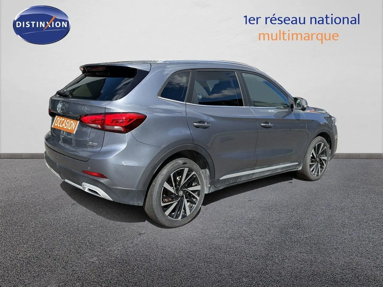Vue 3/4 arrière droite d’un MG ZS 1.5L Hybrid+ 197ch Luxury gris métallisé Hampstead avec jantes alliage bicolores.