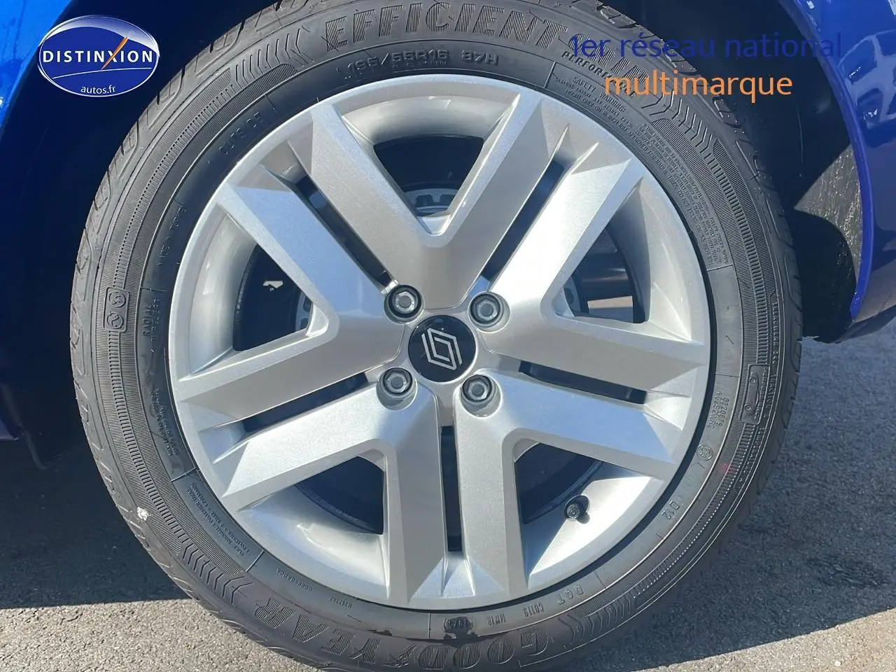 Gros plan sur la roue avant gauche d'une Renault Clio V bleu iron, mettant en valeur la jante alliage et le logo central Renault.